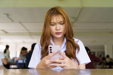 Thai University Student Sitting Alone at Campus Cafe Outdoors Using Phone