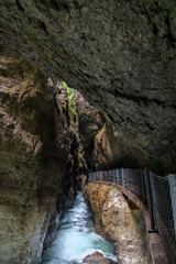 A narrow footpath clings to the rugged cliffs of Partnachklamm Gorge in Garmisch-Partenkirchen,...