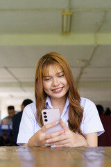 Thai University Student Sitting Alone at Campus Cafe Outdoors Using Phone