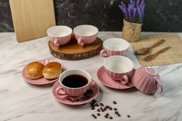 Pastel pink ceramic teacup set with coffee and buns on a marble table. Still life with lavender for...