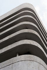 Abstract low-angle view of a brutalist building with curved concrete floors, creating a strong...
