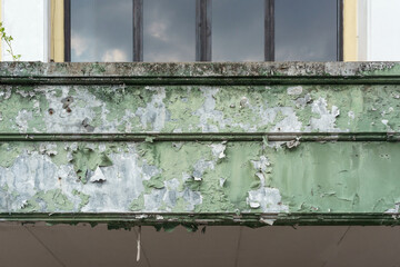 Close-up texture of weathered green paint peeling off an old concrete beam, showing decay and...