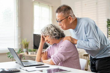 Senior couple checking bills and calculating expenses using a calculator at home, debt taxes and...