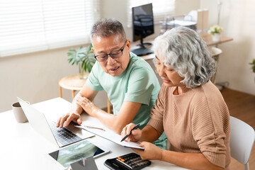 Happy senior couple reading important documents while sitting together at the table at home....