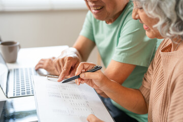 Happy senior couple reading important documents while sitting together at the table at home....