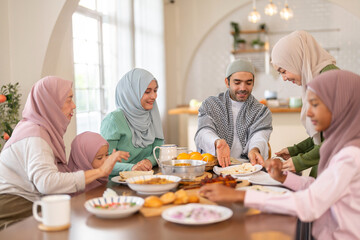 Muslim big family sharing traditional meal together around dining table wearing hijabs and kufi in cultural love, ramadan iftar celebration, eid al-fitr festive, halal meal gathering food culture
