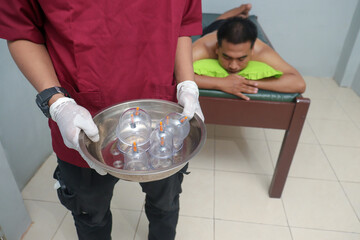 Male therapist preparing cupping therapy tools before treatment. Traditional healing setup for body relaxation, detox, and muscle recovery