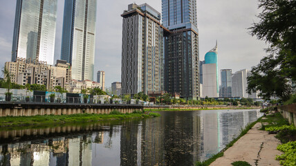 view of a public park with a lake in Jakarta in the morning with a background of modern buildings on the lake side