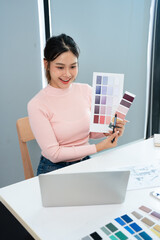 Interior designer talking with client on video call, showing pantone. Asian architect in studio...