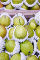 Close-up of fresh ripe fragrant pears protected in white foam netting in fruit market 