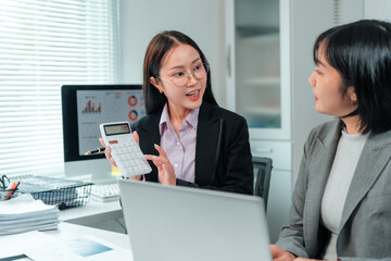 Two asian businesswomen are working together in modern office, analyzing financial data using...