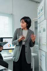 Businesswoman holding a smartphone while presenting infographic charts, explaining business...