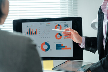 Businesswomen engaging in a meeting, utilizing a computer to display charts and graphs, analyzing...