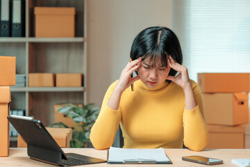 Young business woman having headache while working on a laptop and managing her online store,...