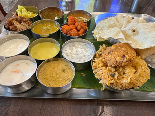Indian vegetarian thali with nineteen verity of vegetable items sweet savoury umami spicy rice chapati biryani chutney papadum top view stainless steel platter