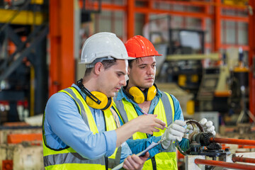 An expert technician is overseeing the production control of metal sheets. Two engineers actively monitor the production line in a metal sheet factory.