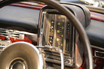 The dashboard of a vintage classic car features detailed analog gauges, a radio, and air vents in...