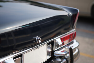 A chrome keyhole above the license plate and a polished rear trunk lock system on a vintage car...