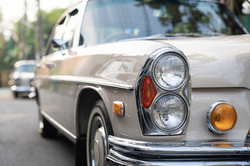 The round headlights and side turn signals on classic cars, framed in polished chrome, highlight...