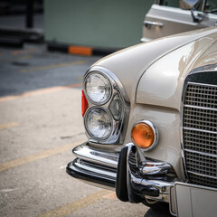 The round headlights and side turn signals on classic cars, framed in polished chrome, highlight...