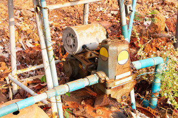 Old water pump motor drilling groundwater from underground on floor and structure with plastic pipe for water circulation. Industrial water technology. Pumps of devices in water supply system.