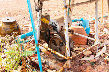Old water pump motor drilling groundwater from underground on floor and structure with plastic pipe for water circulation. Pumps of devices in water supply system. Industrial water technology.