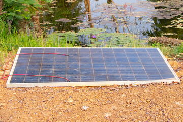Structure old solar cell damaged or solar panel modern technology for energy revolution สeft on ground next to natural pond. Alternative power source to saving environment. Photovoltaic module.
