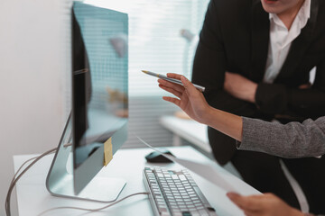 Business colleagues are discussing financial data displayed on a computer screen during a productive meeting in a modern office environment, fostering collaboration and informed decision making