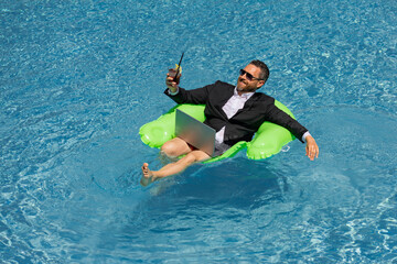 Crazy summer. Business drink summer cocktail and using laptop in suit in water pool. Fun business...