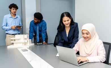 Asian and Muslim women working together on a laptop, With a background as male colleagues...
