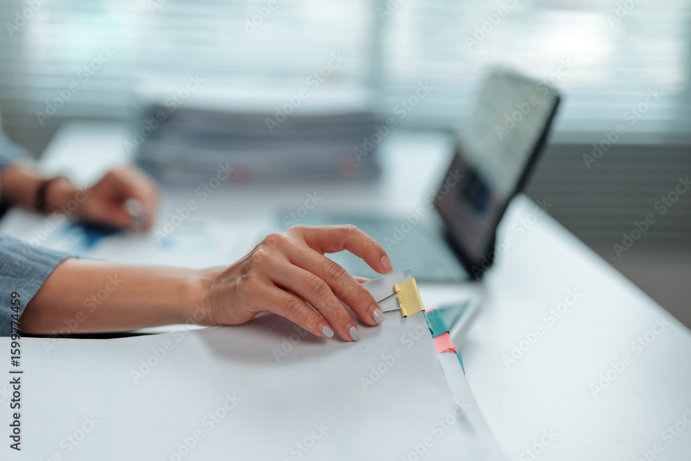 Aufkleber office worker attaching documents with a paper clip while focused on tasks at a modern, tidy desk. b