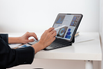 Businesswoman working with a stylus pen and digital tablet, analyzing financial charts and graphs...