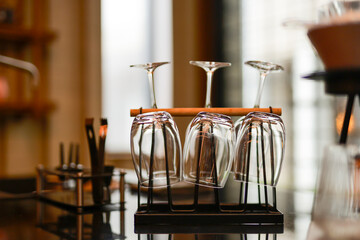 Clean glasses hanging upside down on a metal rack in a cafe, drying and waiting for use by baristas...