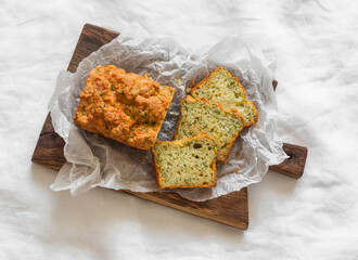 Cheddar cheese, dill, coriander herbs savory cake on a wooden cutting board on light background, top view