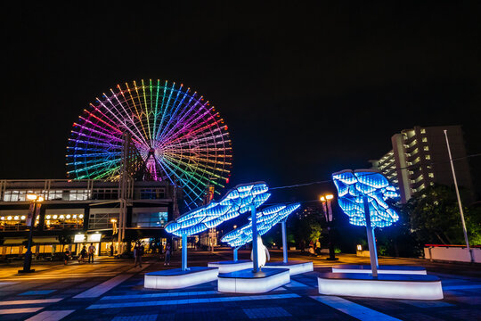 Osaka, Japan &ndash; July 12, 2025: Colorful illuminated ferris wheel and modern art installation glowing at night.