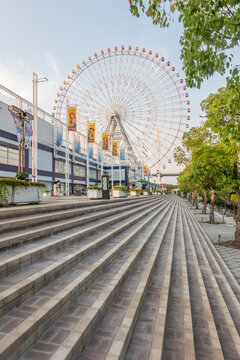 Osaka, Japan &ndash; July 12, 2025: Large ferris wheel and modern shopping complex at Tempozan Harbor Village in late afternoon light.