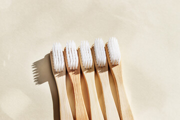 Aesthetic Beige bamboo toothbrushes with white bristles at sunlight on beige background....