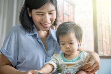 mother reads a storybook to her baby, a mom teaches her child to read, encouraging early learning...