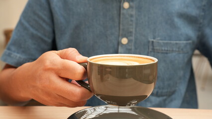 Man holding a cup of coffee latte at cafetaria
