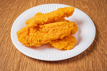 Crispy chicken tenders are artfully arranged on a white plate, tempting your taste buds