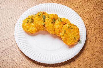 Crispy potato cakes on a white plate, garnished with fresh herbs, are mouthwatering!
