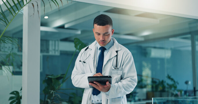 Man, serious doctor and tablet in hospital for research, telehealth or check email with app. Medical worker, tech and reading report for healthcare records, online schedule or test results in clinic