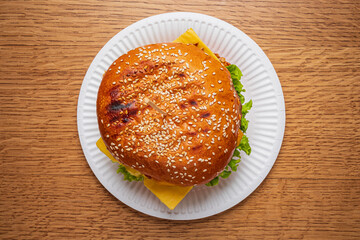 A delicious burger topped with cheese and crisp lettuce sits appetizingly on a paper plate