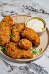 Fried chicken pieces with savory sauce and green onions on a plate