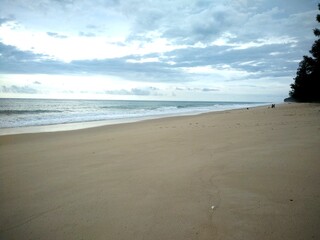 Empty tropical beach with soft golden sand under cloudy sky in Phanga, Thailand
