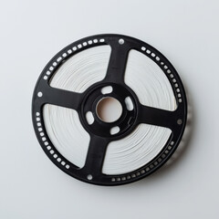 Obraz premium Close up of vintage black film reel with white film, showcasing intricate metallic details and perforations, placed on clean white background