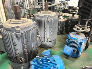 Multiple industrial electric motors placed on a factory floor, used for machinery and heavy-duty...