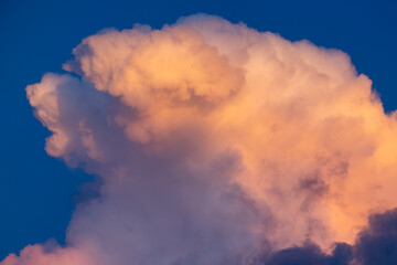 The breathtaking view of a magnificent cloud formation, beautifully illuminated by the vibrant hues of the sunset, showcases natures incredible artistry against the deep blue canvas of the sky
