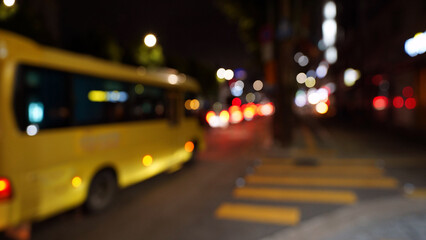 Blurred Night City Lights with School Bus on Late Evening Street