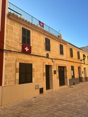 building in Ciutadella Menorca built if Mares stone mines on the island displaying the Menorca flag. An historic building typical of the Balearic Island city of Spain on the coast also with shutters
